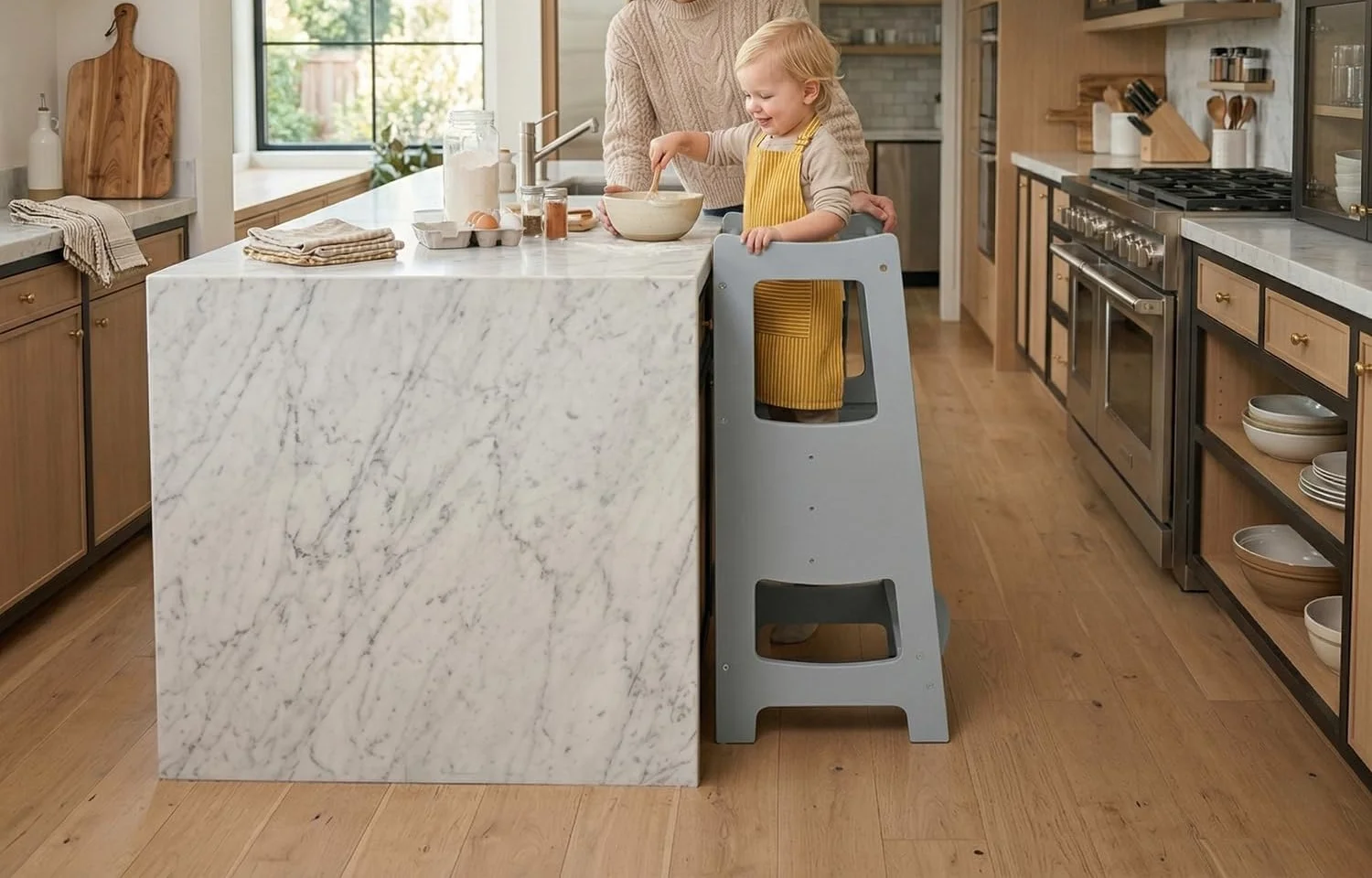 A toddler standing in an EGREE kitchen step stool at a kitchen island